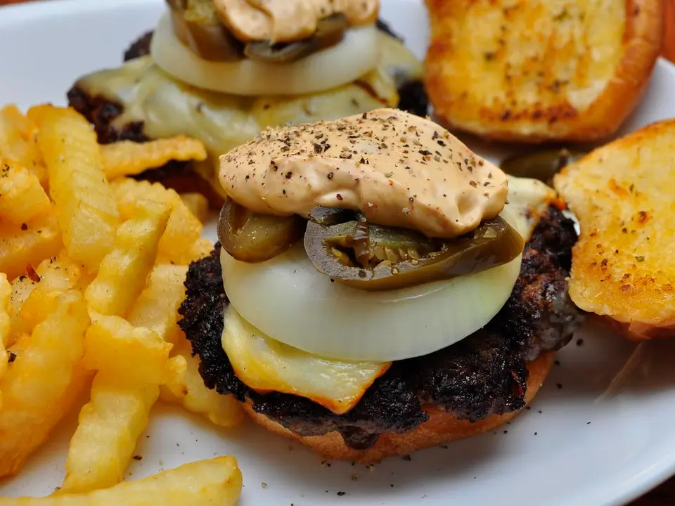 Hambúrguer com cebola, queijo e molho especial ao lado de batatas fritas