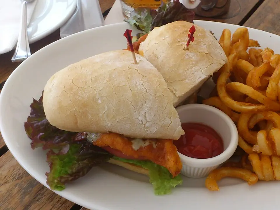 Sanduíche de frango empanado no pão rústico com batatas onduladas