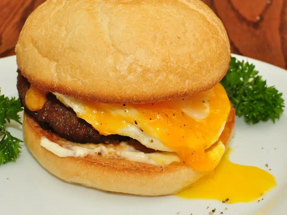 Hambúrguer com ovo de gema mole escorrendo e queijo derretido
